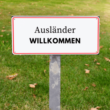 Ein Schild steht auf einer Wiese. Darauf ist zu lesen: Ausländer willkommen.