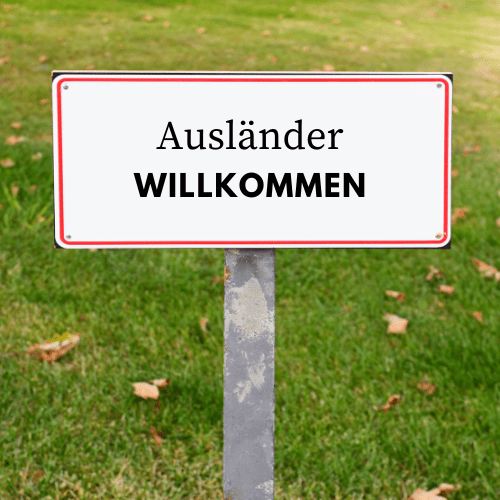 Ein Schild auf einer Wiese. Darauf steht: Ausländer willkomen.