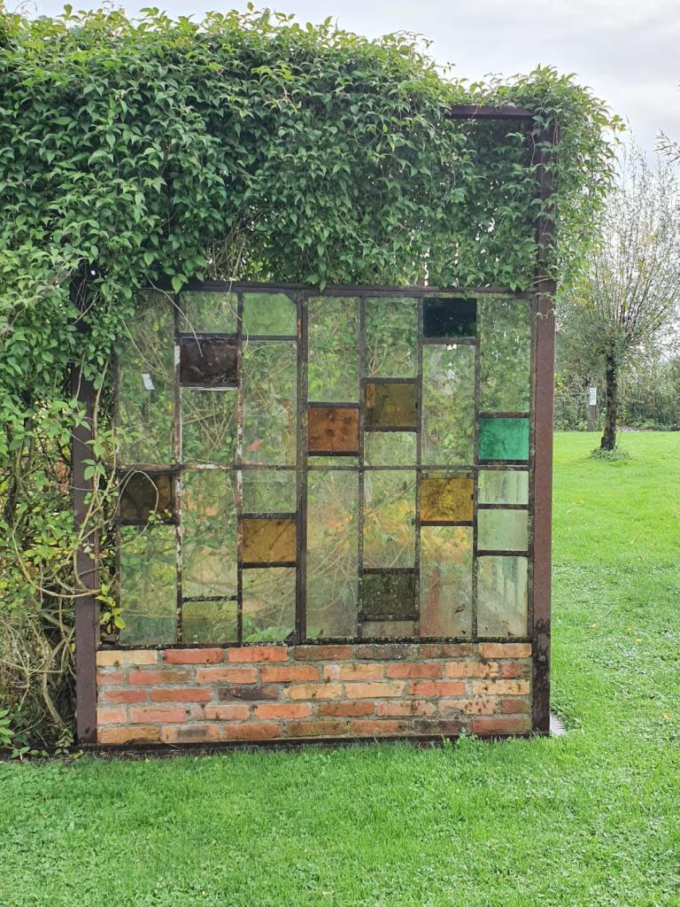 Ein altes Fenster mit Glaseinsätzen dient als Raumteiler und Rankhilfe.