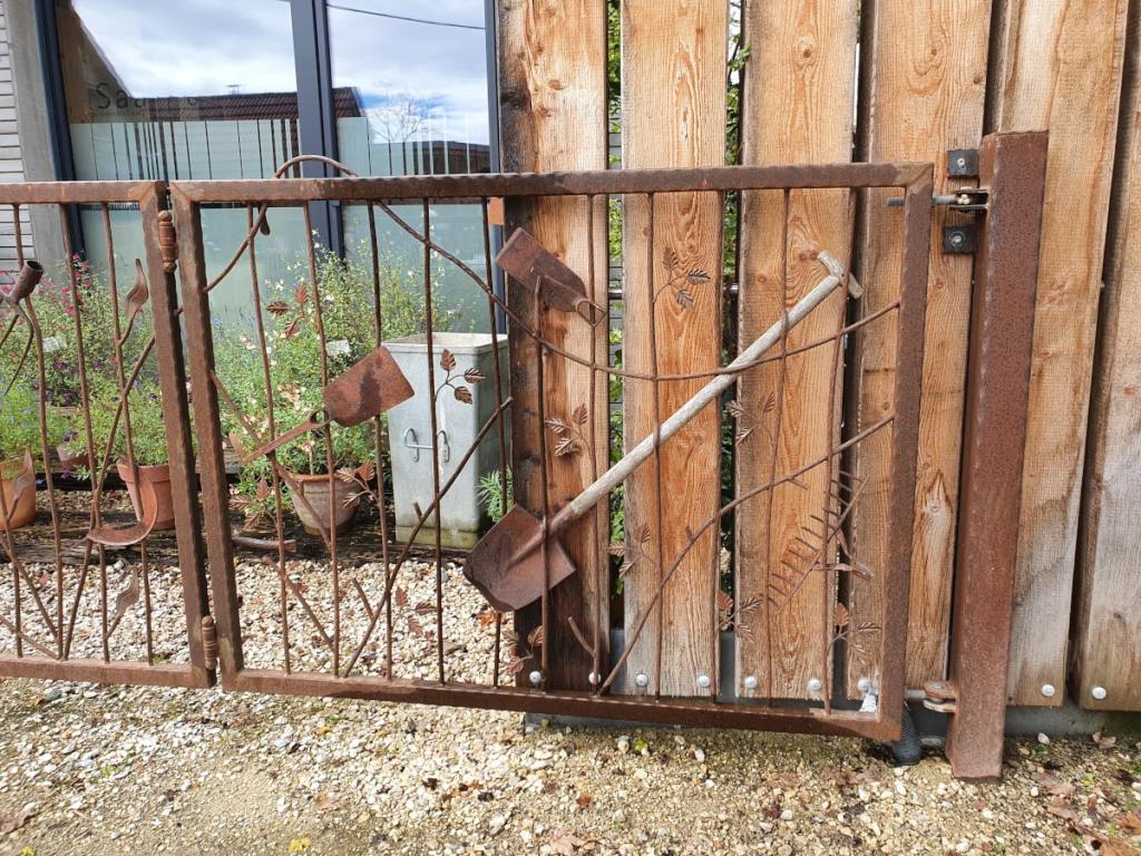 Altes Gartenwerkzeug wurde dekorativ in ein Metalltor integriert.