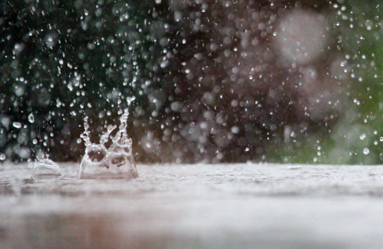 Große Wassertropfen fallen auf die Erde. Das Wasser spritzt in alle Richtungen.
