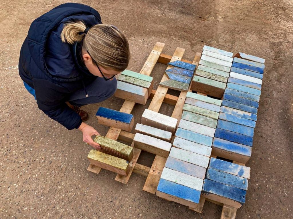 Eine Frau kniet am Boden und betrachtet verschiedene Steine